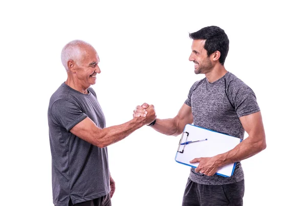 Cliente anziano maschio che stringe la mano nel saluto al fitness trainer prima dell'allenamento. Su uno sfondo bianco isolato. — Foto Stock
