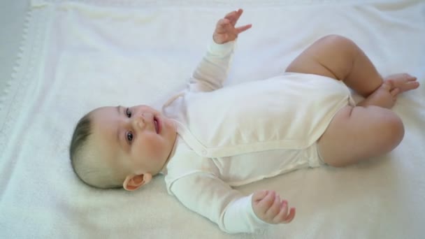 Egy újszülött fekszik elégedett és boldog játék, pozitív érzelmekkel. Mozgó lábak és karok — Stock videók