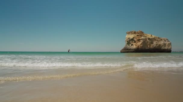 A young man surfer floats on paddleboard on the tropical sea into the far away. — Stock Video