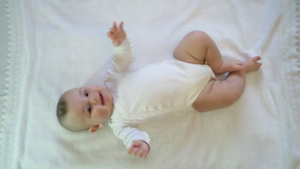 Egy újszülött fekszik elégedett és boldog játék, pozitív érzelmekkel. Mozgó lábak és karok — Stock videók