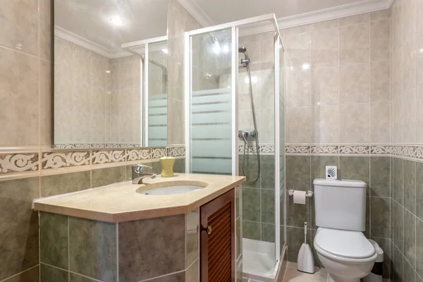 シンプルなベージュをテーマにしたバスルームにはきれいなタオルが飾られています。シャワーの隣にはモダンなシンクがあり、窓の外に照らされています。. — ストック写真