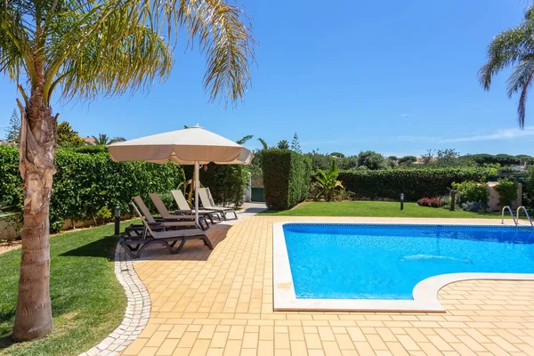 Sale relax posizionate a destra e nella parte anteriore di una piscina con acqua pulita in una giornata di sole. — Foto Stock