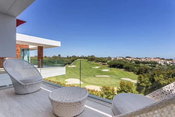 Schöne Aussicht auf die grüne Golfplatzlandschaft vom Luxus-Balkon, mit dekorativen Stühlen und Tisch. lizenzfreie Stockbilder