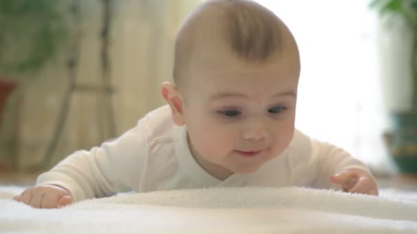 Yeni doğmuş bir bebek, mutlu ve mutlu bir şekilde, pozitif duygularla oynayarak yatar. Karnımın üstünde yatıyorum, yatak odasına bakıyorum.. — Stok video