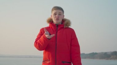 Avrupalı bir adam, kırmızı ceketli, bir rap şarkısı söylüyor. Denizde, sahnenin ortasında..