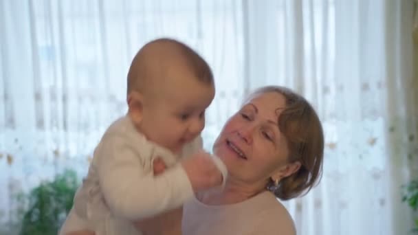 Een schattige gepensioneerde oma, spelend met haar geliefde kleinzoon, in de logeerkamer. Houdt haar armen vast, close-up — Stockvideo