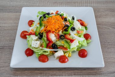 Taze malzemeli geleneksel Yunan salatası, beyaz arka planda beyaz kaplama seramik tabakta beyaz peynir, zeytin, kırmızı domates. Üst görünüm, kapat.