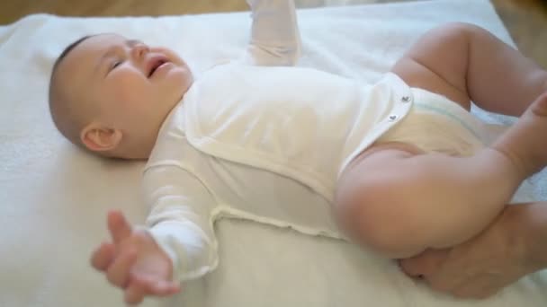 Une jeune mère met des vêtements pour un petit garçon, sur le lit, il pleure malheureux. Fermer à l'intérieur. — Video