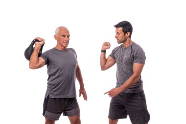 Bir spor eğitmeni ve yaşlı bir adam, bir müşteri, kettlebell egzersizi yaparlar. Beyaz arka planda. Spor salonu reklamı için..