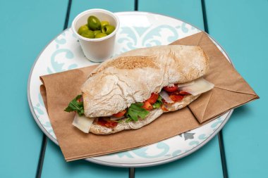 Sucuklu, peynirli ve otlu ekmek sandviçi. Yeşil azeitonlar. Hint yemeği. Yakın plan..