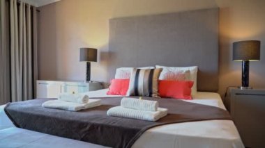 Otelde yatağı olan, dinlenmek için evi olan, rahat, modern bir yatak odası. Katlanmış havlular. Masa lambalı komodinlerin yanında..