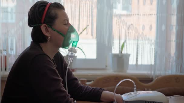 Μια Ευρωπαία, στο σπίτι, πραγματοποιεί εισπνοή, εισπνοή ατμών πετρελαίου, οξυγόνο μέσω μάσκας. Θεραπεία πνευμονίας, βρογχίτιδας. Κοντινό πλάνο. — Αρχείο Βίντεο