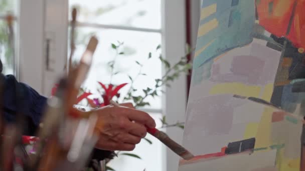 Die Künstlerin trägt Farbe mit Pinselstrichen auf die Leinwand auf, Pinsel in Nahaufnahme. Abstrakte Malerei. Zeitlupe — Stockvideo