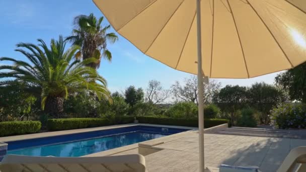 Casa de vacaciones de lujo con piscina y jardín. Con tumbonas y sombrillas en la terraza, movimiento lateral. — Vídeo de stock