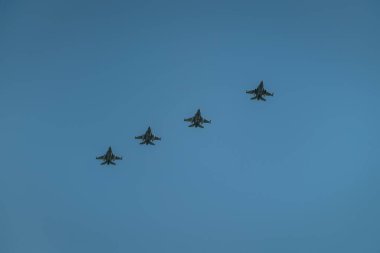 Mavi arka planda dört uçak. Bir grup profesyonel pilot geçit töreni sırasında gökyüzünde numaralar gösteriyor.