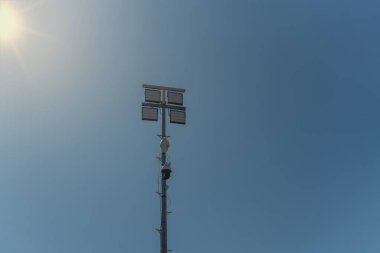 Suç bölgesinde güvenlik kameraları olan bir sokak direği ve gece lambaları. Mavi gökyüzüne ve güneşe karşı.