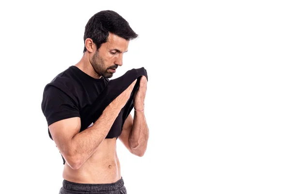 Europeisk man, kaukasier, idrottsman, torkar svett från pannan med T-shirt. Efter ett hårt träningspass. Stress och trötthet. På en vit bakgrund. — Stockfoto