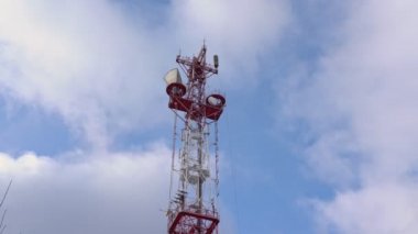 Mavi gökyüzü ve hareket eden bulutların arka planına karşı televizyon ve radyo yayın anteninin alt görüntüsü. Akıllı telefonlar için 5G frekansının geliştirilmesi tartışması.
