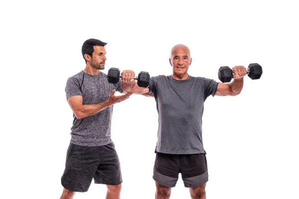 Ein alter Mann mit Personal Trainer macht ein Fitnesstraining. Auf einem isolierten weißen Hintergrund. Weißer Hintergrund. — Stockfoto