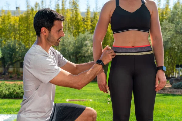 A fitness trainer measures the waist of a client on a weight loss program, diet and training. Solving the problem of obesity. — Stock fotografie