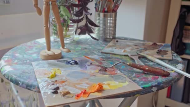 Art workshop. Palette with paints on the table. Drawing tools. Sunlight shines through the window. Close-up. — Stock videók