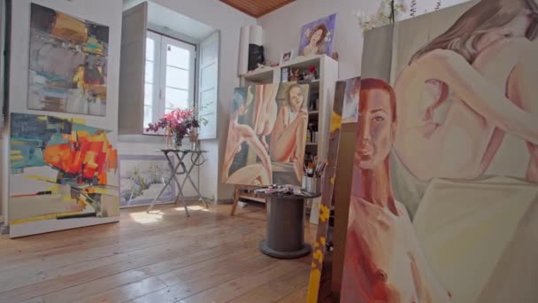 Art workshop, gallery, studio. Painted pictures with acrylic paints. Sunlight shines through the window. Conceptual photography. — Wideo stockowe