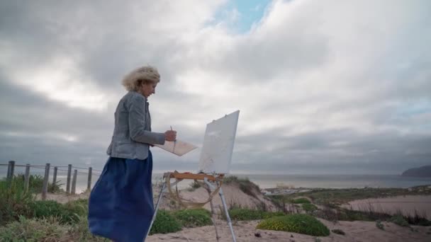 Europäerin mittleren Alters, Künstlerin, malt eine Meereslandschaft mit einem originellen Blick auf das Meer. Zeitlupe — Stockvideo