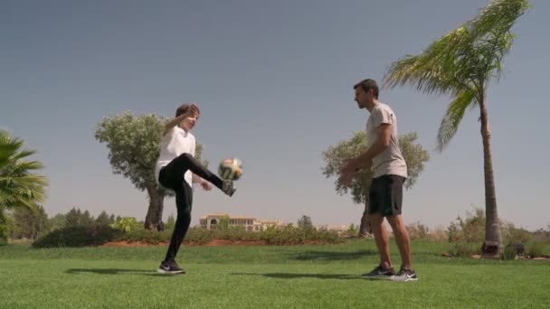 Ein Mann mittleren Alters trainiert mit einem jungen Mann im Park. Koordinationstraining. Tritt den Ball mit dem Fuß. — Stockvideo
