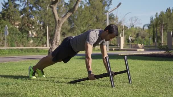 Sportler mittleren Alters im Park beim Training. Liegestütze auf einer Sprosse, die am Boden liegt. Kniebeuge. — Stockvideo