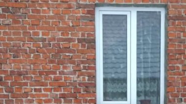 Kış sıkıcı dramatik sahne, arka planda kırmızı tuğla bir duvarın üzerine düşen kar. Yavaş çekim.