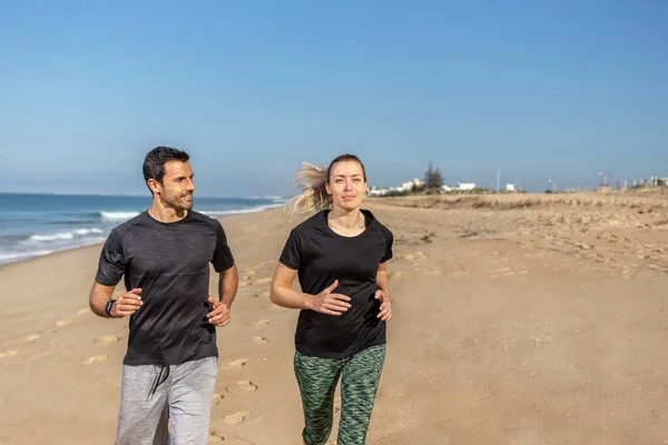 Un entrenador de fitness y un cliente, una mujer europea, se dan la mano. Feliz y contento. Contra el fondo del mar en verano. — Foto de Stock