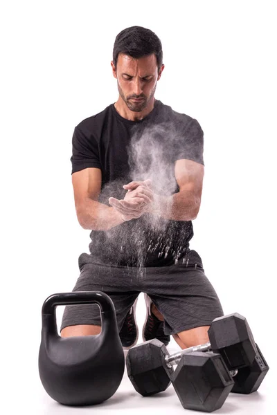 Der europäische Athlet bereitet sich auf das Training vor, klatscht mit Kreide in die Hände und hebt eine Wolke empor. Auf einem weißen, isolierten Hintergrund. mit Gewichten, — Stockfoto