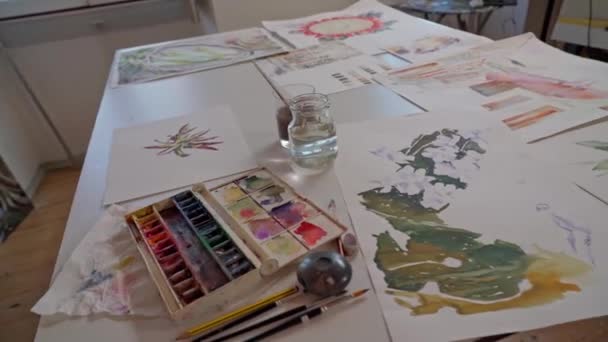 Kunstwerkstatt. Die Zeichnungen auf dem Tisch sind mit Aquarellen gefertigt. Nahaufnahme. — Stockvideo