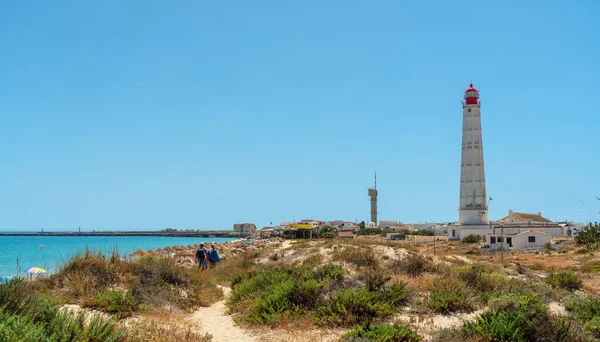 Utsikt över stranden på den portugisiska ön Farol med en fyr och ett par promenader längs stigen. Ría Formosa — Stockfoto