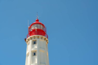 Mavi gökyüzüne karşı kırmızı kapaklı beyaz bir deniz feneri. Her şeyin gidişatı için kavramsal bir sinyal. Boşluğu kopyala