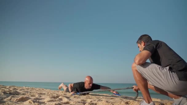 一名冲浪运动员用双手在木板上、海滩上模拟划船，由一名教练教冲浪技巧。葡萄牙Faro 2021 — 图库视频影像
