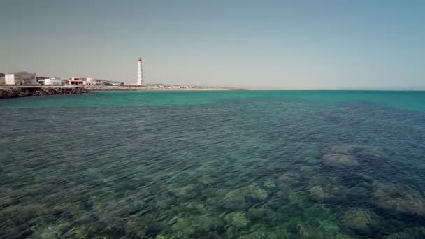 Ilha de Farol. Algarve. Portekiz. Sakin okyanus turkuazdır. Arka plandaki deniz feneri — Stok video