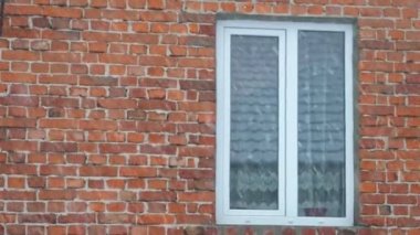 Kış sıkıcı dramatik sahne, arka planda kırmızı tuğla bir duvarın üzerine düşen kar. Yavaş çekim.