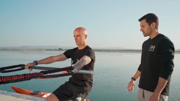 A windsurfer on a stabilization ball stimulates riding on a board with rubber expanders. To develop equilibrium and stability. Portugal Faro 2021 March 15 — Stock Video