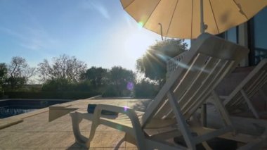Bahçeye bakan bir geçit havuzu ve bahçesi olan lüks bir tatil evi. Verandadaki güneş pansiyonları ve şemsiyelerle.