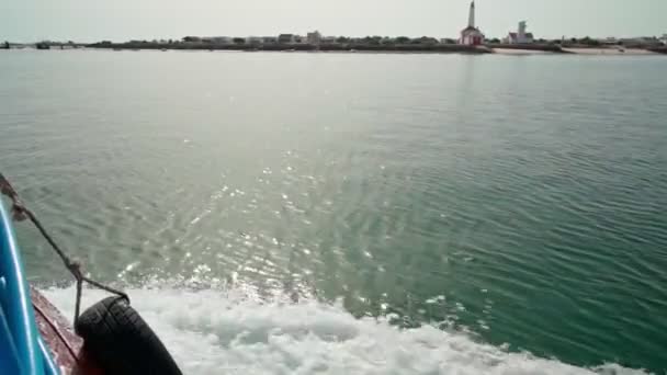 Ilha de Farol vagyok. Algarve vagyok. Portugália.Utazz hajóval az óceánon. A tiszta, nyugodt tenger hullámai feltörnek a hajóra. A világítótorony a háttérben — Stock videók