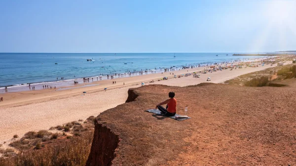 Una mujer de mediana edad, durante unas vacaciones en Portugal, se sienta en una alfombra en un acantilado, frente al mar y medita. —  Fotos de Stock