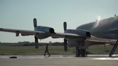 Kazadan sonra acil iniş yapan ve motorları aşırı ısınan bir Amerikan askeri uçağı. Asistan ısıtılmış motorların üzerine su döker..