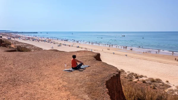 Una mujer de mediana edad, durante unas vacaciones en Portugal, se sienta en una alfombra en un acantilado, frente al mar y medita. —  Fotos de Stock