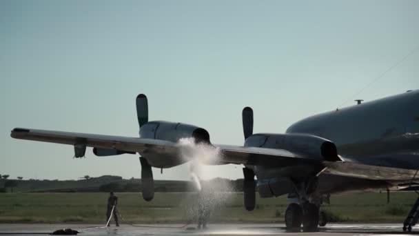 Un avión militar estadounidense, con un aterrizaje de emergencia después de un accidente y sobrecalentamiento de los motores. El asistente vierte agua en los motores calentados. — Vídeo de stock