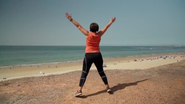 Frauen mittleren Alters, fettleibig, springen für Gewichtsverlust und Figur, in Zeitlupe. Direkt am Meer mit Blick auf den Strand. — Stockvideo