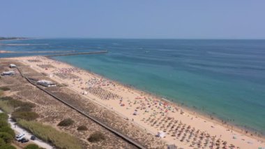 Hava videosu, güzel Portekiz plajları, turist kasabası yakınlarındaki, Vilamoura, Falesia, rıhtım manzaralı. Turistler güneşleniyor..