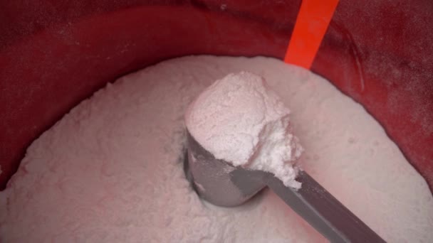 Tournage d'une macro extrême, s'éloignant d'une tasse à mesurer avec de la poudre de protéines blanches, la glutamine, dans un réservoir. Vue du dessus. — Video