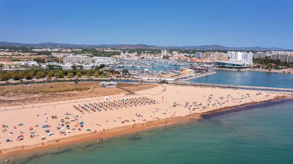 Widok z lotu ptaka na luksusową plażę Falesia w Vilamoura. Z opalaniem turystów na leżakach. Port Marina z jachtami, w tle. — Zdjęcie stockowe