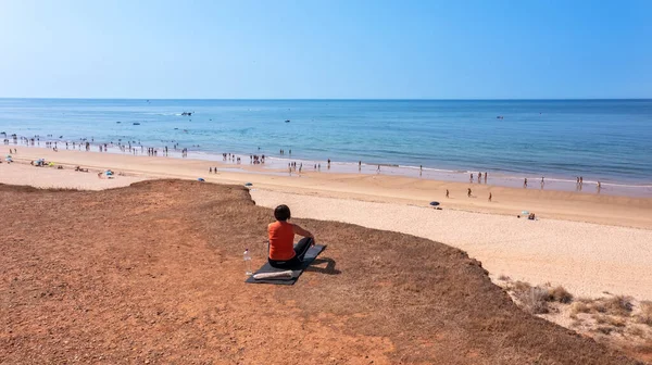 Una mujer de mediana edad, durante unas vacaciones en Portugal, se sienta en una alfombra en un acantilado, frente al mar y medita. —  Fotos de Stock